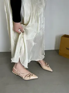 Detail view of stylish beige patent leather slingback kitten heels with delicate straps.