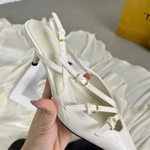 White patent leather pointed toe slingback kitten heels with buckle straps and thin high heels.