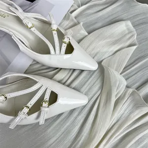 Elegant white patent leather pointy toe slingback kitten heels with chic buckled straps.