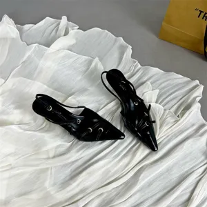 Black patent leather pointed toe slingback kitten heels with straps and metal ring details.