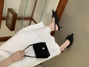 Black polka dot pointed toe slingback heels shoes detail view showcasing fashion style.