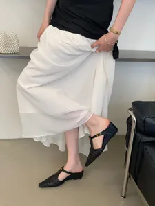 Vista detallada de elegantes zapatos mules trenzados con punta y tacón de cuña bajo.