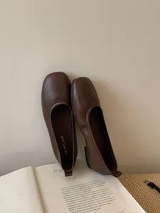 Close-up detail of vintage brown soft-sole flat shoes resting on a book in lifestyle scene.