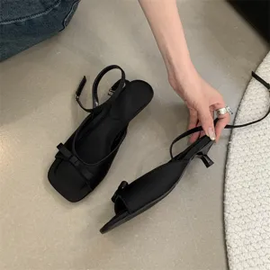 Detailansicht schwarzer Slingback-Sandalen mit Schleife und filigranem Pfennigabsatz.