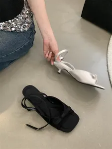 Nahaufnahme von französischen Kitten-Heel-Sandalen mit Schleife und schickem Knöchelriemen.