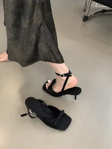Detailansicht schwarzer französischer Stiletto-Sandalen mit Schleife und Knöchelriemen.