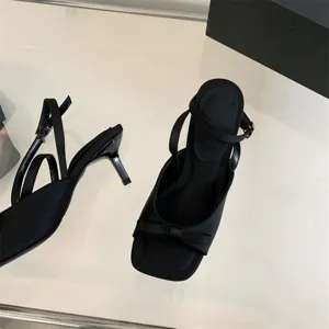 Detailaufnahme eleganter schwarzer High Heels mit quadratischer Zehenpartie und Schleife.