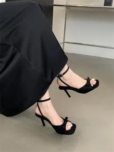 Detailaufnahme schwarzer Damen High Heel Sandaletten mit eleganter Schleife und Knöchelriemen.