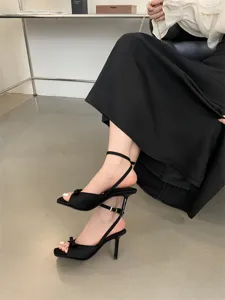 Detailansicht eleganter schwarzer High Heels mit Schleife und filigranem Knöchelriemen.
