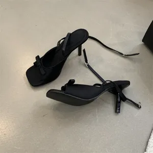 Elegante schwarze Stiletto-Sandalen mit feinen Riemchen, offener Zehenpartie und Schleife.