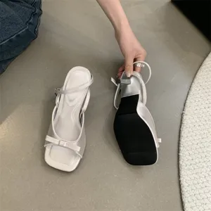 Detailansicht eleganter französischer High-Heel-Sandalen mit schicker Schleife und Knöchelriemen.
