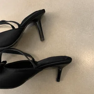 Schwarze Damen Pantoletten mit hohem Stilettoabsatz und Riemen, elegante Sommerschuhe.