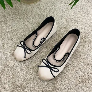 Eleganti ballerine beige e nere con grazioso fiocco e cinturino di perle alla moda.