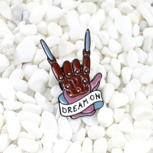 Detailed view of the punk rock skeleton hand enamel brooch with dream on banner design.