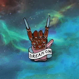Punk rock skeleton hand enamel pin with sharp blade fingers and dream on banner brooch badge.
