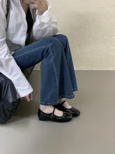 Schwarze flache Mary Jane Schuhe mit Lochmuster, zartem Riemen und Metallschließe.