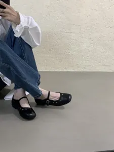 Detailansicht schwarzer, flacher Mary Jane Schuhe mit modischem Lochmuster und feinem Riemen.