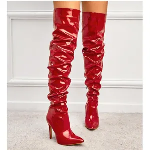 Red patent leather stiletto over-the-knee boots with pointed toe and side zipper.