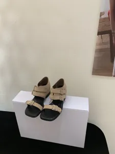 Primo piano dei sandali con fibbia beige minimalisti retrò con delicato design a doppia fascia.