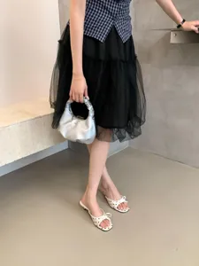 Primer plano detallado de elegantes sandalias de tacón sensato para mujer con lunares y lazos.