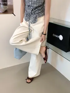 Primer plano de elegantes sandalias de tacón bajo con lunares y lazo con pantalón blanco.