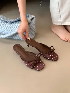 Vista detallada de elegantes zapatos de tacón marrón con lunares y un lazo bonito.