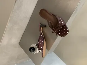 Primer plano de elegantes sandalias de tacón bajo con lunares marrones y bonito lazo.