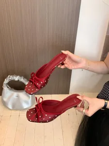 Vista detallada de mules rojos de lunares con tacón bajo cuadrado y lazo elegante.