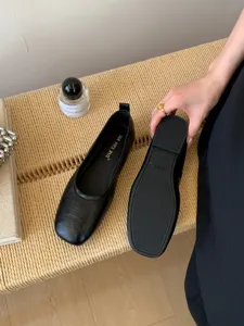 Detail view of black square-toe flat shoes, soft leather material, elegant retro design.