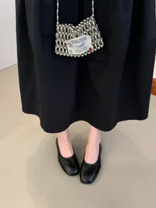 Close-up detail of black flat mary jane shoes paired with a beaded mini bag.