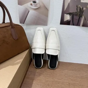 Vista dettagliata di eleganti mules bianche da donna con punta quadrata, stile old money chic.