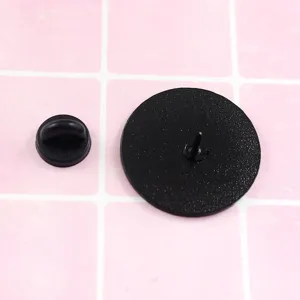 Detail view of the black round brooch back showing secure metal pin and rubber clutch.
