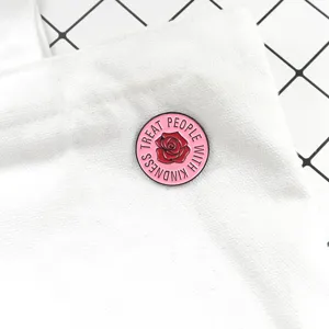Close-up detail of a cute pink enamel lapel pin with red rose and inspirational text.