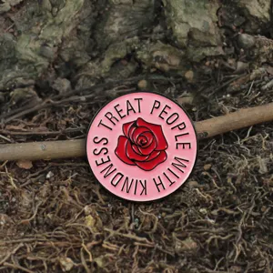 Close-up detail of pink enamel brooch featuring red rose and inspiring message text.