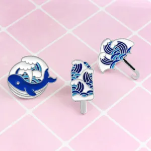Set di spille in smalto con design di balena, gelato e ombrello con motivi di onde blu.