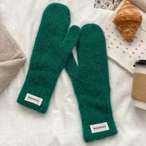 Green fuzzy knit mittens detail shot, soft plush warm winter gloves with stylish label.