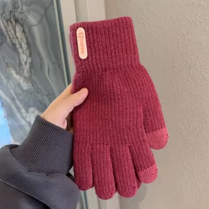 Primo piano di guanti invernali in maglia touch in rosa scuro con tessuto caldo.