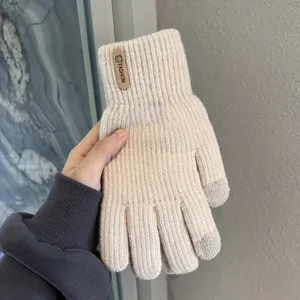 Primo piano dettaglio di guanti invernali in maglia touch beige con punte delle dita conduttive.
