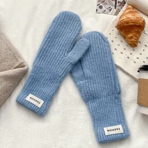Detailed view of warm winter blue knitted mittens featuring cozy ribbed cuffs and chic tags.