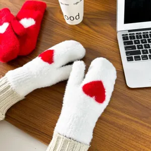 Cozy fuzzy white winter mittens detail shot with red heart pattern on wooden desk setup