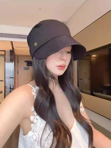 Close-up view of a chic black straw bucket hat with side metal button and back bow tie detail.