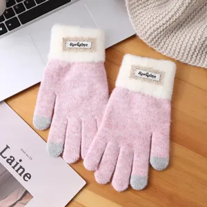 Close-up of pink knitted winter touchscreen gloves with white plush cuffs and cute lace label.