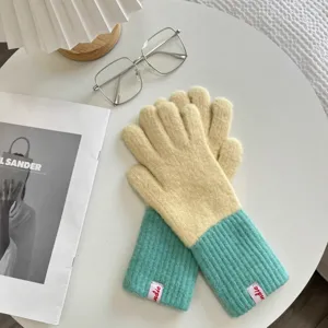 Detailed view of women's color-blocked knit gloves in yellow and mint green for winter.