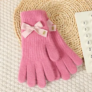 Pink knit winter gloves with cute bow detail, warm cozy handwear close up product detail.