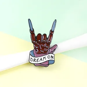 Punk skeleton hand enamel pin detail shot, featuring a cool rock gesture and Dream On banner.