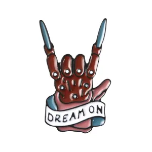 Punk style metal enamel pin featuring a creepy razor glove hand design with Dream On text banner.