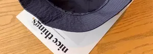 Detail shot of the dark blue quick-drying bucket hat resting on a stylish magazine surface.