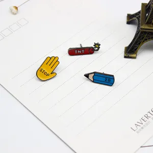 Detailed view of creative cartoon enamel lapel pins featuring pencil, bomb, and stop hand gesture.
