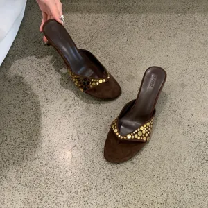 Sandalias de tacón alto de ante marrón vintage con elegantes detalles de tachuelas doradas.