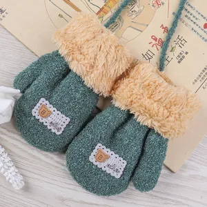 Close-up of cozy kids winter mittens, soft coral fleece with cute bear patch and neck strap.